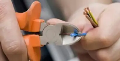 licensed electrician performing precise wire cutting and preparation during electrical service in Redding, CA