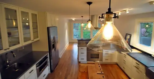 Residential electrician installing modern indoor light fixture in a home in Redding, CA